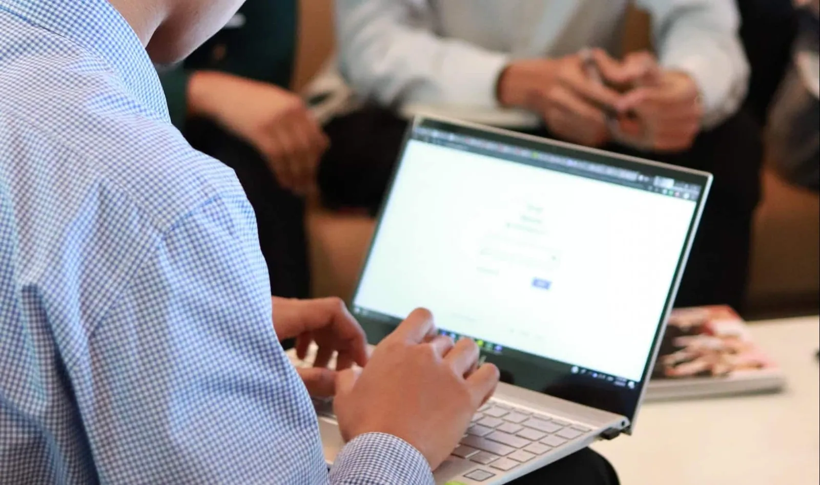 man working on his laptop with coworkers in background